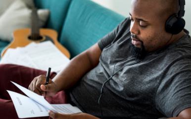 Un homme écoute un podcast avec un casque audio assis sur un canapé